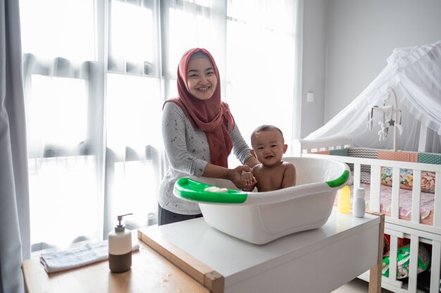 Mère musulmane lave le petit garçon dans la baignoire