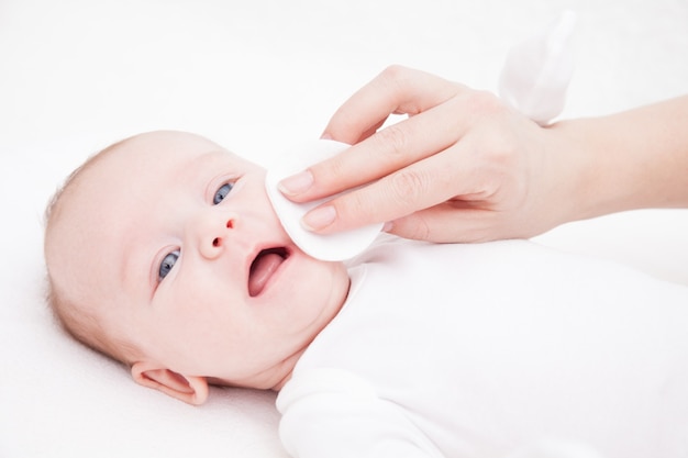 Photo mère nettoie le visage d'un nouveau-né avec un coton