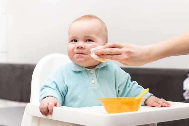 Mère nettoyant la bouche d'un bébé affamé