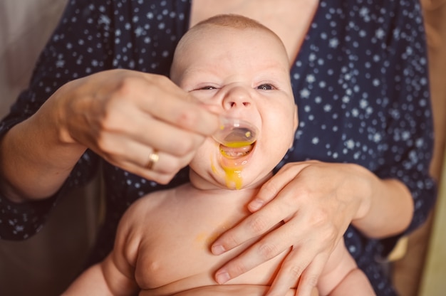 Mère et nouveau-né drôle de bébé qui pleure émotionnellement bébé garçon nu prend des médicaments liquides ou