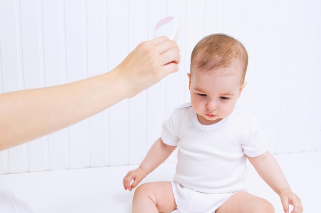 La mère peigne de beaux cheveux de babys