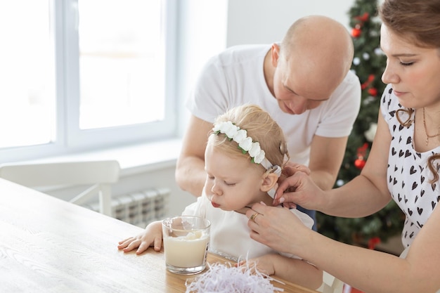 Mère et père aident à mettre un implant cochléaire pour leur petite fille sourde dans le salon de noël espace de copie Prothèse auditive et technologies médicales innovantes concept de traitement de la surdité