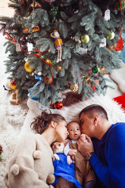 La mère, le père, le chien et le bébé sont allongés sur le sol près de l&#39;arbre de Noël