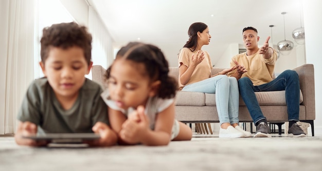 Mère père et désaccord sur le canapé du salon pendant que les enfants jouent avec une tablette sur le sol à la maison Maman et papa se disputent ou se disputent dans une situation difficile sur un canapé en litige