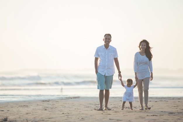 Mère et père enseigne à sa fille se promène sur la plage