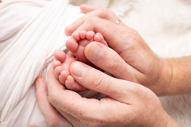 Mère et père font un massage sur son pied de bébé Gros plan sur les pieds de bébé dans les mains de la mère Prévention du développement des pieds plats Dysplasie du tonus musculaire Famille amour soins et concepts de santé