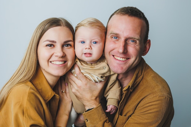 Photo une mère et un père heureux tiennent leur fils de 4 mois dans leurs bras photo de famille de parents heureux avec un nouveau-né concept de famille