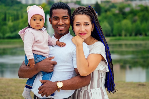 Mère et père interracial transnational marchant avec leur petite fille métisse dans le parc d'automne