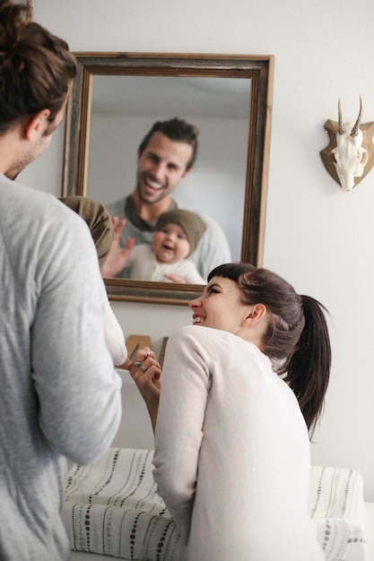 Une mère et un père avec leur bébé se regardant dans le miroir