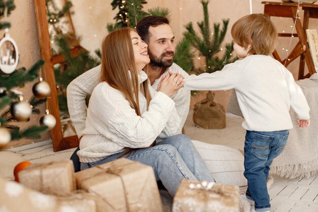 Mère père et leur fils assis près de l'arbre de Noël à la maison