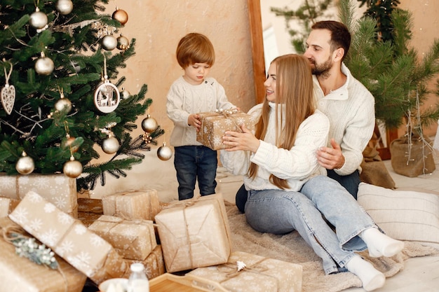 Mère père et leur fils assis près de l'arbre de Noël à la maison