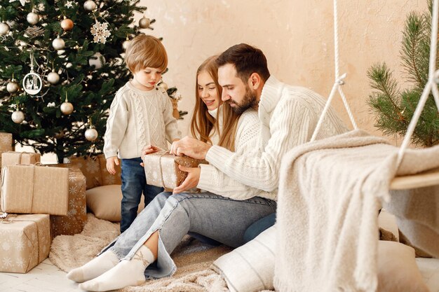Mère père et leur fils assis près de l'arbre de Noël à la maison