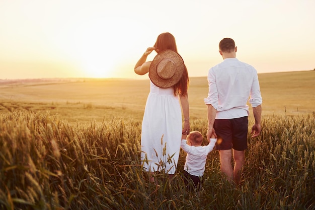 Mère et père avec leur fils passant du temps libre sur le terrain à l'heure ensoleillée de l'été Vue de derrière