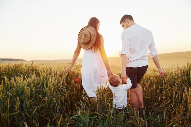 Mère et père avec leur fils passant du temps libre sur le terrain à l'heure ensoleillée de l'été Vue de derrière