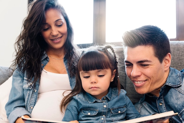 Mère et père lisant un livre à leur fille à la maison.