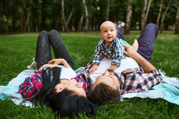 Mère, père et petit bébé loisirs sur l'herbe