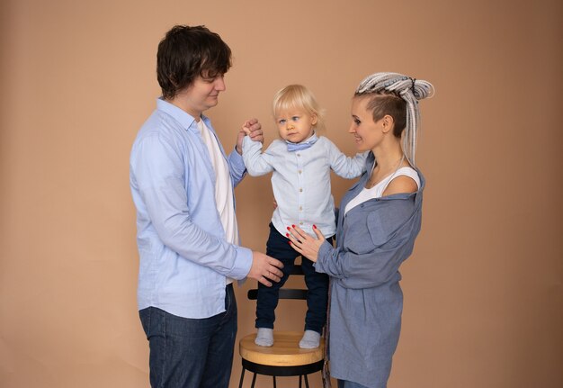 Mère et père et petit fils isolé sur mur beige