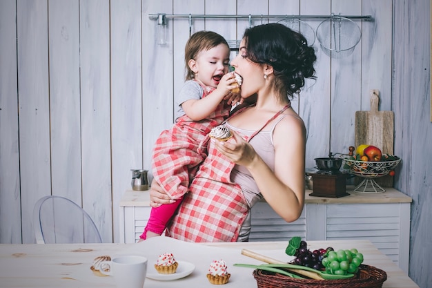 Mère et petit enfant dans la cuisine à la maison avec des tabliers