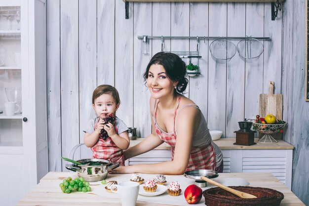 Mère et petit enfant dans la cuisine à la maison avec des tabliers