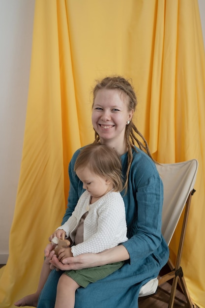 Une mère et un petit enfant jouent avec un jouet en bois Maman et sa fille sont assises sur une chaise et