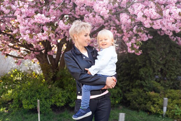 Mère et petit fils s'amusent dans les jardins fleuris de Sakura Portrait woman hugging little baby boy