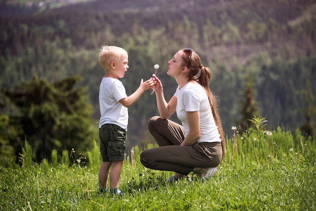 Mère et petit fils soufflent le pissenlit. Maternité et amitié