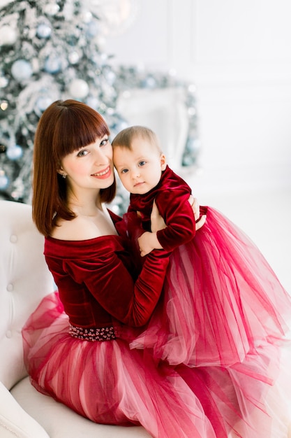 mère avec petite fille, assise sur un fauteuil sur le fond de l'arbre de Noël