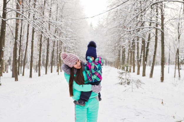 Mère et petite fille de bébé marchant dans la forêt d'hiver et s'amusant avec la neige. Famille