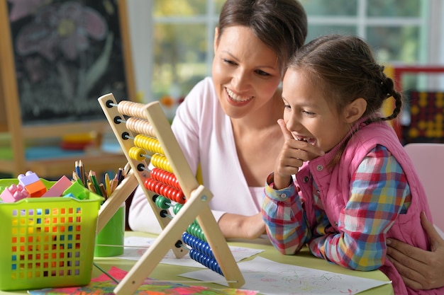 mère avec petite fille comptant avec boulier à la maison