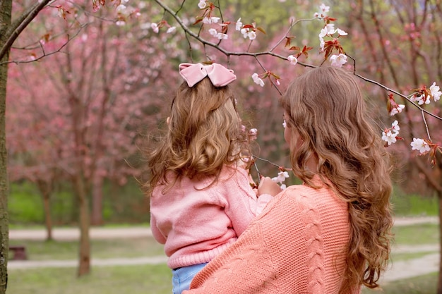 Mère et petite fille dans le parc sous un cerisier en fleurs