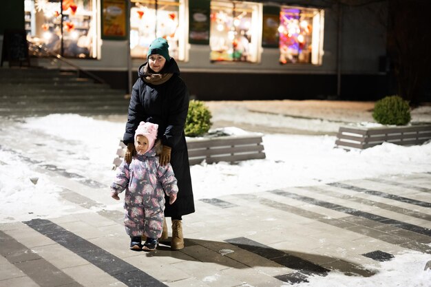 Mère et petite fille dans la ville de nuit en hiver Maman avec sa fille en soirée