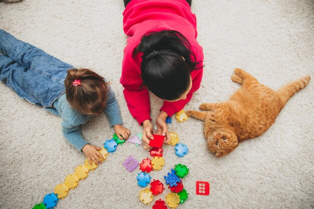 Mère et petite fille jouent au constructeur sur le tapis du salon. famille heureuse