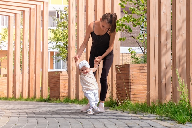 La mère et la petite fille marchent dans la cour de la ville, l'enfant apprend à marcher