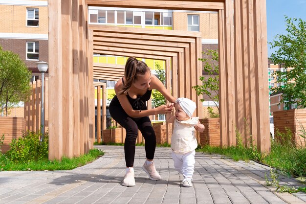 La mère et la petite fille marchent dans la cour de la ville, l'enfant apprend à marcher