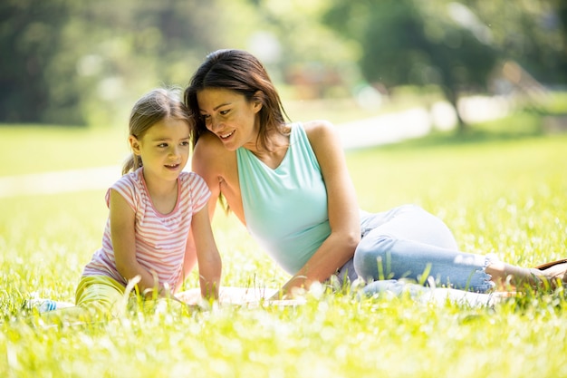 Mère avec la petite fille mignonne s'amusant sur l'herbe au parc