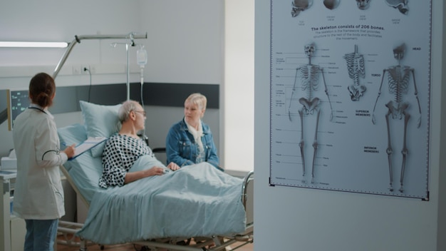 Mère et petite fille visitant un homme âgé dans un lit d'hôpital, apportant un bouquet de fleurs lors de la visite. Les visiteurs surprennent le vieux grand-père et aident à la récupération médicale. Famille à la clinique