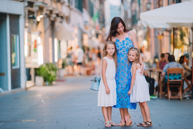 Mère avec petites filles mignonnes manger des glaces dans la rue