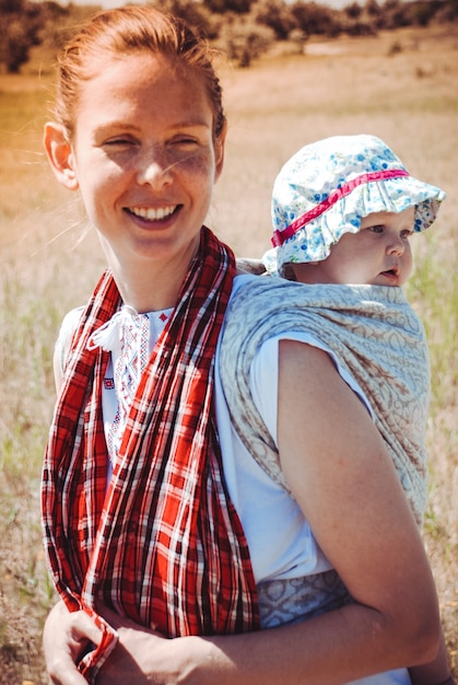 Photo mère portant son petit enfant dans un porte-bébé