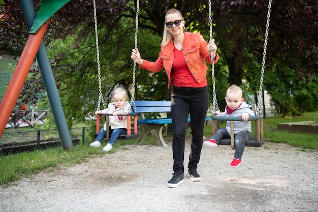 Mère poussant son bébé s'amusant sur la balançoire