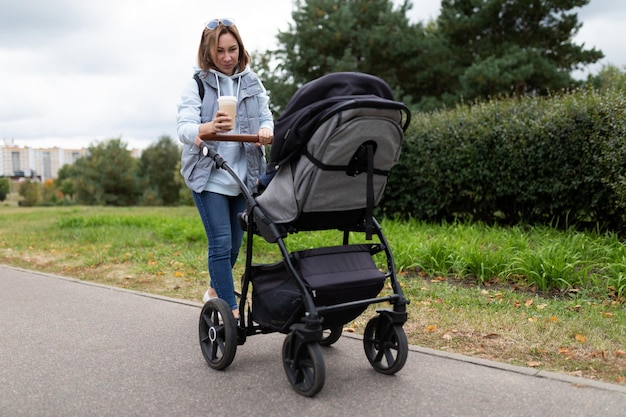 Mère avec une poussette avec un enfant dans le parc pour une promenade