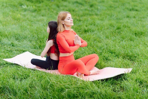 Mère pratiquant le yoga avec sa fille en plein air