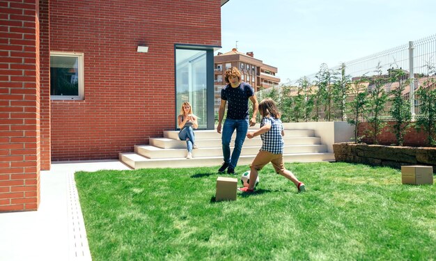 Mère prenant une photo mobile de son mari et de son fils jouant dans le jardin