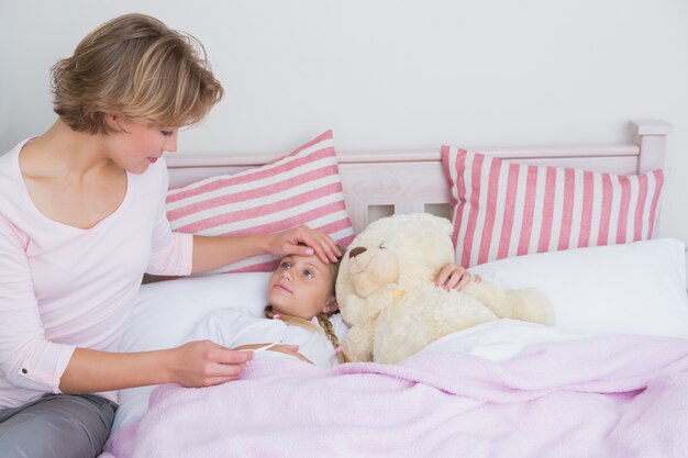 Mère prenant la température de la fille malade