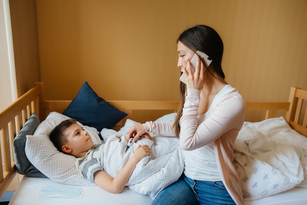 Une mère prend soin de son enfant qui a de la fièvre et de la fièvre. Maladie et soins de santé.