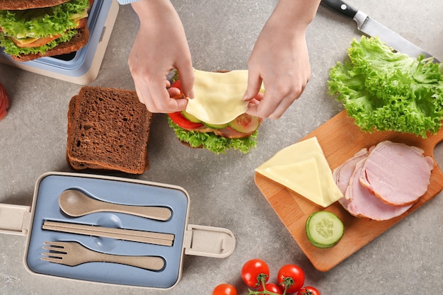 Mère préparant un sandwich pour le déjeuner scolaire sur la table