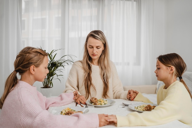 Mère priant avec les enfants à table