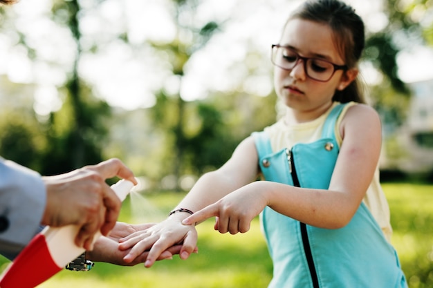 Photo mère pulvérisant des insectifuges sur la peau de sa fille.