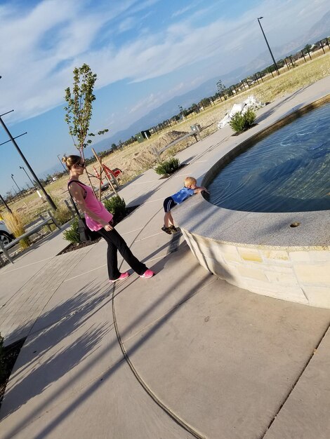 Mère regardant son fils jouer près de la fontaine par une journée ensoleillée