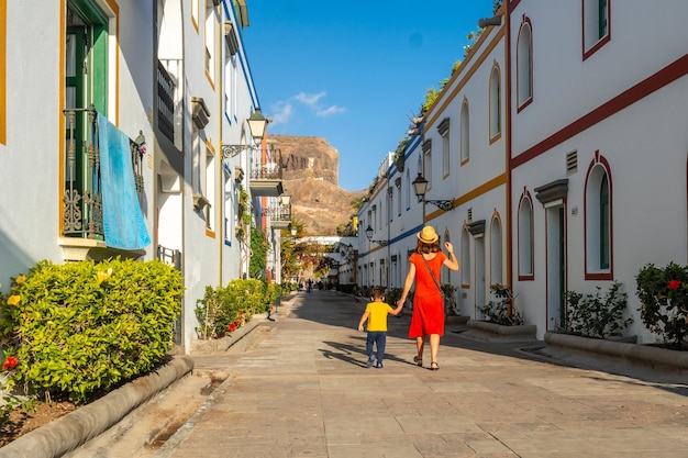 Mère en robe rouge et son fils marchant dans le port de la ville de Mogan à Gran Canaria Vacances en famille