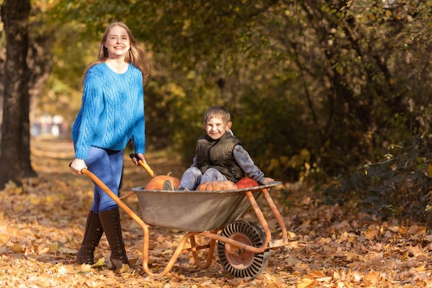 La mère s'amuse avec les enfants utilise une brouette de jardin